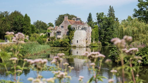 A view across the moat towards the old castle with flowers in the foreground